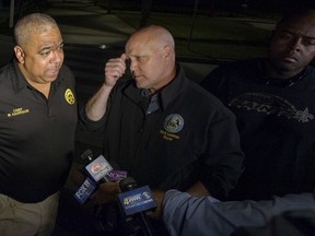 From left, New Orleans Police Superintendent Michael Harrison talks to the media, as Mayor Mitch Landrieu and 7th District Commander Lawrence Dupree, right, listen outside University Medical Center, early Friday, Oct. 13, 2017 in New Orleans, La.  A New Orleans police officer was shot and killed early Friday, ambushed while getting out of a patrol car to investigate something which had aroused suspicions on the city's east side, police said.   (Matthew Hinton/The Advocate via AP)