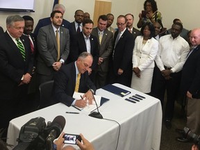 In this June 15, 2017 photo, a bipartisan group of lawmakers surround Louisiana Gov. John Bel Edwards as he signs 10 criminal justice bills into law during a ceremony in Baton Rouge, La. Hundreds of inmates are about to get early releases from Louisiana prisons and jails, a milestone in a push to reduce the nation's highest incarceration rate. The early release of roughly 1,500 inmates on Nov. 1 is the product of a new package of laws overhauling the state's criminal justice system. (AP Photo/R.J. Rico)