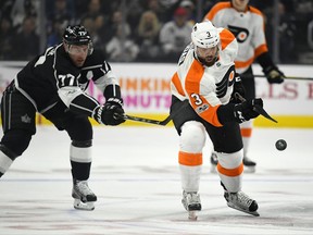 Philadelphia Flyers defenseman Radko Gudas, right, of the Czech Republic, passes the puck while under pressure from Los Angeles Kings center Jeff Carter during the first period of an NHL hockey game, Thursday, Oct. 5, 2017, in Los Angeles. (AP Photo/Mark J. Terrill)