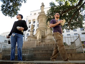 FILE - In this Nov. 4, 2011 file photo, Sean Bordelon, left, and Raphiel Heard, of Shreveport, pause after reading the inscription on the Confederate soldier's monument in front of the Caddo Parish Courthouse in Shreveport, La. Local officials have voted to remove the Confederate monument from the courthouse grounds in the northwest Louisiana parish. The Caddo Parish Commission voted 7-5 for the measure on Thursday, Oct. 19, 2017, after hearing nearly two hours of opinions about the monument erected 111 years ago in a parish once called "Bloody Caddo" because so many African-Americans were killed during Reconstruction.   (Douglas Collier /The Shreveport Times via AP)