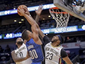 Orlando Magic forward Aaron Gordon (00) tries to shoot over New Orleans Pelicans forward DeMarcus Cousins (0) and forward Anthony Davis (23) in the first half of an NBA basketball game in New Orleans, Monday, Oct. 30, 2017. (AP Photo/Scott Threlkeld)