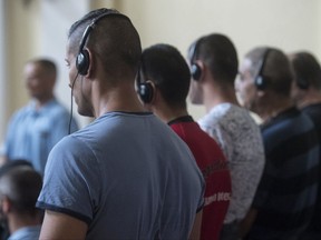 FILE - In this June 21, 2017 file photo defendants stand in the courtroom at the beginning of the trial against eleven defendants charged with involvement in the death of 71 migrants who suffocated in a refrigerated truck which passed through Hungary and was discovered in Austria, near Parndorf, in 2015 at the tribunal in Kecskemet, 85 kms southeast of Budapest, Hungary. Prosecutors say an Afghan man and two Bulgarian men were part of the same trafficking organization involved in the 2015 case. (Sandor Ujvari/MTI via AP, file)