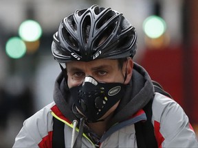 A cyclist wears a mask in central London, Monday, Oct. 23, 2017. The Mayor of London Sadiq Khan officially launched T-Charge on Monday. The T-Charge will be the toughest vehicle emissions standard of any world city, affecting the oldest and most polluting vehicles. (AP Photo/Kirsty Wigglesworth)