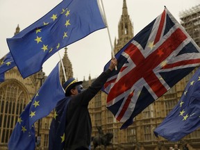 Pro-EU supporters hold European Union flags with a Union flag across the street from the Houses of Parliament in London, Tuesday, Oct. 17, 2017. (AP Photo/Matt Dunham)