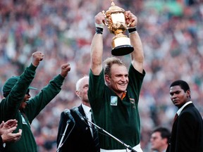 FILE - In this June 24, 1995, file photo, South African rugby captain Francios Pienaar, center, raises the trophy after receiving it from South African President Nelson Mandela, left, who wears a South African rugby shirt, after they defeated New Zealand in the final 15-12 at Ellis Park, Johannesburg.  South Africa on Tuesday Oct. 31, 2017 was recommended as the best host for the 2023 Rugby World Cup ahead of France and Ireland. (AP Photo/Jan Hamman, File)