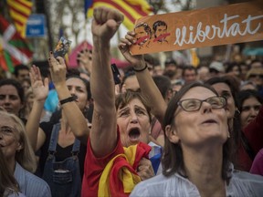 FILE- In this Friday, Oct. 27, 2017 file photo, people react as they watch the parliament session on a huge screen during a rally outside the Catalan parliament in Barcelona, Spain. Pro-independence Catalans are cheering the regional parliament's declaration of secession from Spain, a country they don't regard as their own. (AP Photo/Santi Palacios, File)
