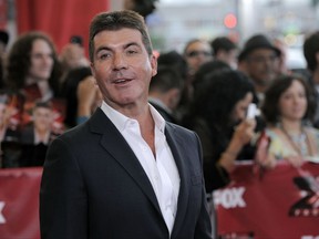 FILE - In this file photo dated Wednesday, Sept. 14, 2011, Simon Cowell, executive producer and a judge on "The X Factor," poses at a world premiere screening event for the new television series, in Los Angeles, USA.  According to a British national newspaper report Friday Oct. 27, 2017, entertainment mogul Simon Cowell has been hospitalized after a fall at his London home. (AP Photo/Chris Pizzello, FILE)