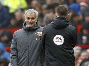Manchester United manager Jose Mourinho, left, exchanges words with fourth official Stuart Attwell during the game against Tottenham Hotspur, during their English Premier League soccer match at Old Trafford in Manchester, England, Saturday Oct. 28, 2017. (Martin Rickett/PA via AP)