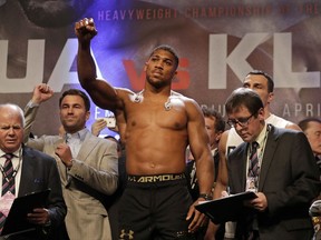 FILE- In this Friday, April 28, 2017 file photo, British boxer Anthony Joshua gestures as he takes part in the weigh-in for his fight against Ukrainian boxer Wladimir Klitschko at Wembley Arena in London. Joshua fights Carlos Takam on Saturday in a mandatory defense of his WBA and IBF heavyweight belts. (AP Photo/Matt Dunham, File)