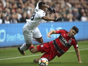 Swansea City's Jordan Ayew, left, and Huddersfield Town's Christopher Schindler clash in action during their English Premier League soccer match at the Liberty Stadium in Swansea, England, Saturday Oct. 14, 2017. (Nick Potts/PA via AP)