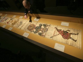 A member of British Library staff poses for a picture pointing at the Philosopher's Stone on the 16th-century Ripley Scroll, which describes how to make a Philosopher's Stone, at the "Harry Potter - A History of Magic" exhibition at the British Library, in London, Wednesday Oct. 18, 2017.  The exhibition running from Oct. 20, marks the 20th anniversary of the publication of Harry Potter and the Philosopher's Stone, showing items from the British Library's collection, and items from author J.K Rowling and the book publisher's collection. (AP Photo/Tim Ireland)