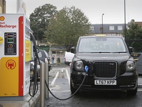 A new TX Cab London taxi is plugged into a charging station during a media opportunity at a Shell petrol station on Holloway road, in London, Wednesday Oct. 18, 2017, 2017. Only days after Shell agreed to buy electric vehicle charging firm NewMotion, Shell are opening three charging stations Wednesday with more expected by the end of the year.  (AP Photo/Tim Ireland)