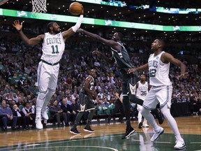 Boston Celtics guard Kyrie Irving (11) grabs a rebound against Milwaukee Bucks forward Thon Maker, center, during the first quarter of an NBA basketball game, Wednesday, Oct. 18, 2017, in Boston. At right is Boston Celtics center Al Horford. (AP Photo/Charles Krupa)