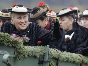 A woman in her costume of the region salutes with liqueur as she sits in a horse-drawn carriage during the traditional Leonhardi pilgrimage in Warngau, Germany, Sunday, Oct. 22, 2017. The annual pilgrimage honors St. Leonhard, patron saint of the highland farmers for horses and livestock. (AP Photo/Matthias Schrader)