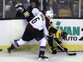 Colorado Avalanche defenseman Erik Johnson (6) slams Boston Bruins left wing Jake DeBrusk (74) against the boards as they pursue the puck in the first period of an NHL hockey game, Monday, Oct. 9, 2017, in Boston. (AP Photo/Steven Senne)