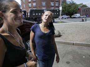 In this Wednesday, Aug. 23, 2017 photo Jamie Allison, left, stands with a resident of the Mattapan neighborhood of Boston, on the street near a strip of land sometimes referred to as "Methadone Mile," in Boston. Tobin says she is in a methadone program, and had just come from Narcotics Anonymous meeting when she ran into Allison. (AP Photo/Steven Senne)