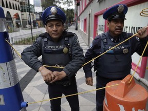 In this Oct. 17, 2017 photo, police block access to a closed section of pedestrian Genova Street, where an 11-story building was heavily damaged in the Sept. 19 earthquake, in the Zona Rosa neighborhood of Mexico City. Local businesses are calling for quick demolition of the damaged building at Genova 33 and the reopening of the block to allow business to return to the busy commercial and tourist district. (AP Photo/Rebecca Blackwell)