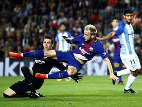 FC Barcelona's Ivan Rakitic, center, falls during the Spanish La Liga soccer match between FC Barcelona and Malaga at the Camp Nou stadium in Barcelona, Spain, Saturday, Oct. 21, 2017. (AP Photo/Manu Fernandez)