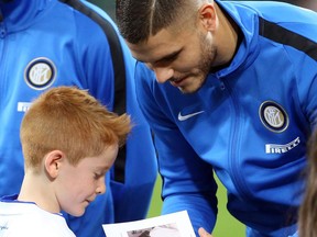Inter's captain Mauro Icardi hands  Anne Frank's diary to a child after signing it, prior the Italian Serie A soccer match between Inter and Sampdoria at the San Siro stadium in Milan, Italy, Tuesday Oct. 24, 2017. Anne Frank's diary will be read aloud at all soccer matches in Italy this week, the Italian soccer federation announced Tuesday after shocking displays of anti-Semitism by fans of the Rome club Lazio. (Matteo Bazzi/ANSA via AP)