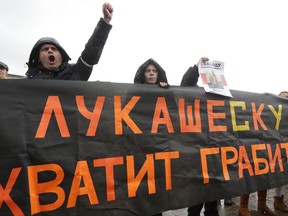 Belarusian opposition activists rally in the city center in Minsk, Belarus, Saturday, Oct. 21, 2017. Around 200 people have rallied in the Belarusian capital of Minsk, calling for the resignation of the president who has ruled the former Soviet republic since 1994. Part of a banner is visible and in its entirety reads -  "Lukaschesku, you are freak! Stop robbing our people". (AP Photo/Sergei Grits)