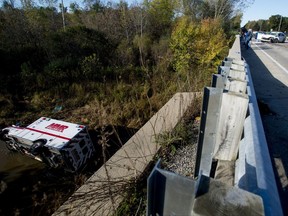 An Mobile Medical Response ambulance rests in Misteguay Creek Monday, Oct. 16, 2017, after colliding with a white Chevrolet Impala on a bridge in Maple Grove Township, Mich. The driver of the car has died and two emergency workers are injured after the Monday crash.  (Jacob Hamilton/The Saginaw News via AP)