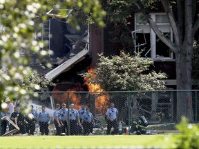 FILE - In this Aug. 2, 2017 file photo, emergency personnel move away as a gas fire continues to burn following an explosion at Minnehaha Academy in Minneapolis. The family of a school receptionist is suing over an explosion that killed her at Minnehaha Academy in Minneapolis this summer. Ruth Berg's family is seeking at least $50,000 in damages. Berg and 82-year-old custodian John Carlson were killed and nine others injured when the building fell on Aug. 2. The lawsuit alleges that contractors for CenterPoint Energy "ran to save themselves" rather than warn people inside the school about the gas leak that caused the explosion. (David Joles/Star Tribune via AP File)