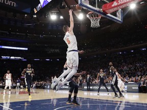 New York Knicks' Kristaps Porzingis (6) catches a lob pass from Courtney Lee for a dunk in front of Denver Nuggets' Wilson Chandler, blocked from view, during the second half of an NBA basketball game Monday, Oct. 30, 2017, in New York. The Knicks won 116-110. (AP Photo/Frank Franklin II)
