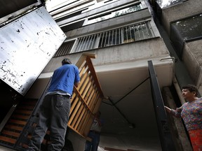 Movers carry a bed frame from a condemned building in the Condesa neighborhood of Mexico City, Tuesday, Oct. 3, 2017. Across Mexico City, some 40 buildings collapsed in the Sept. 19 earthquake and hundreds of others were so severely damaged they will either have to be demolished or receive major structural reinforcement. (AP Photo/Marco Ugarte)