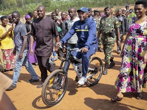 FILE - In this July 21, 2015 file photo, President Pierre Nkurunziza, center, arrives by bicycle, accompanied by first lady Denise Bucumi Nkurunziza, right, to cast his vote for the presidential election, in Ngozi, Burundi. An International Criminal Court spokesman confirmed Friday, Oct. 27, 2017 that Burundi is becoming the first country to withdraw from the court with effect Friday, a year after the East African nation notified the United Nations secretary-general of its intention to leave the court that prosecutes the world's worst atrocities. (AP Photo/Berthier Mugiraneza, File)