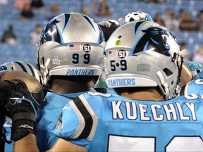 Carolina Panthers' Luke Kuechly (59) and Kawann Short (99) wear a #51 decal on their helmets as they warm up before an NFL football game against the Philadelphia Eagles in Charlotte, N.C., Thursday, Oct. 12, 2017. The 51 is in honor of former Carolina Panthers linebacker and coach Sam Mills, who died of cancer. (AP Photo/Mike McCarn)