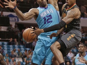 Atlanta Hawks' Kent Bazemore, right, passes the ball around Charlotte Hornets' Dwight Howard, left, during the first half of an NBA basketball game in Charlotte, N.C., Friday, Oct. 20, 2017. (AP Photo/Chuck Burton)