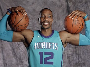 In this Sept. 25, 2017 file photo Charlotte Hornets' Dwight Howard wears the team's new uniform with the Michael Jordan "Jumpman" logo as he poses during the NBA basketball team's media day in Charlotte, N.C. The NBA's new uniform contract with Nike could be a financial coup for Hornets owner Michael Jordan. Sports' greatest pitchman will be reaping the benefits of the Hornets being the only NBA team to wear the famous Jordan Brand "Jumpman" logo on their jerseys this season. (AP Photo/Chuck Burton)