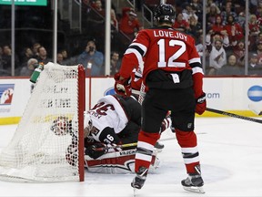 Arizona Coyotes' Christian Fischer (36) falls on top of New Jersey Devils goalie Cory Schneider after scoring a goal during the first period of an NHL hockey game, Saturday, Oct. 28, 2017, in Newark, N.J. New Jersey Devils' Ben Lovejoy (12) looks on. (AP Photo/Adam Hunger)