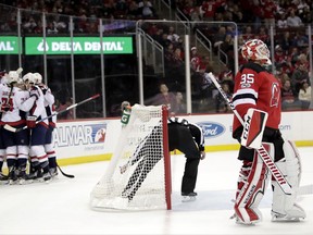 Washington Capitals, left, celebrate a goal by T.J. Oshie as New Jersey Devils goalie Cory Schneider stands near the goal during the first period of an NHL hockey game, Friday, Oct. 13, 2017, in Newark, N.J. (AP Photo/Julio Cortez)