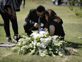 Miguel Cervantes comforts his niece Chantel Sosa as she cries at the graveside during a funeral for her brother Erick Silva, Thursday, Oct. 12, 2017, in Las Vegas. Silva, who was working as a security guard, was killed during a mass shooting Oct. 1, in Las Vegas. (AP Photo/John Locher)