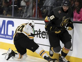 Vegas Golden Knights defenseman Colin Miller (6) eyes the puck with Boston Bruins left wing Jake DeBrusk (74) falling behind him during an NHL hockey game at T-Mobile Arena, Sunday, Oct. 15, 2017, in Las Vegas. (AP Photo/L.E. Baskow)