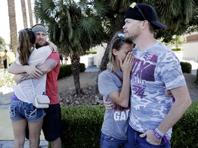 Sean Bean, of Livermore, Calif., hugs his girlfriend Katie Kavetski, of San Leandro, Calif., left, as Travis Reed, of Mexico, Ind., right, comforts his girlfriend Anna Travnicek, second from right, on Las Vegas Strip, Monday, Oct. 2, 2017, in Las Vegas. All attended a concert where a mass shooting occurred on Sunday. (AP Photo/Marcio Jose Sanchez)