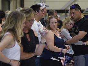 Concertgoers embrace as they wait early Monday, Oct. 2, 2017, inside the Sands Corporation plane hangar after a mass shooting in which dozens were killed  at the Route 91 Harvest country festival early Sunday. (Al Powers/Invision/AP)