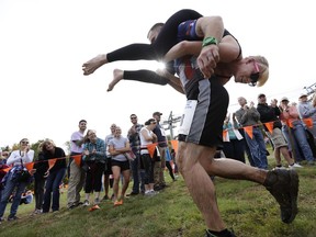 FILE - In this Oct. 8, 2016 file photo, Jaime Devine is carried by her husband, Thomas Devine, of Boston, Mass., during the North American Wife Carrying Championship at the Sunday River Ski Resort in Newry, Maine.  Dozens of participants are vying for cash and beer  in the North American Wife Carrying Championship. More than 60 couples are registered, and more are on a waiting list, for the annual event Saturday, Oct. 7, 2017 at the Sunday River in Maine.(AP Photo/Robert F. Bukaty, File)