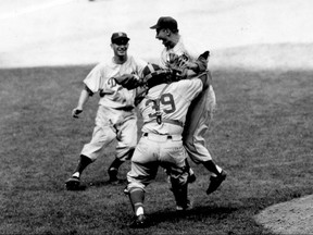 FILE - In this Oct. 4, 1955, file photo, Brooklyn Dodgers pitcher Johnny Podres is lifted by catcher Roy Campanella (39) after the final out of the seventh and deciding game of the World Series at Yankee Stadium in New York. Running toward them is third baseman Don Hoak. Four times in the previous eight years, the Dodgers had reached the World Series and lost to the Yankees. In 1955, this beloved group finally brought Brooklyn the title. (AP Photo/FIle)