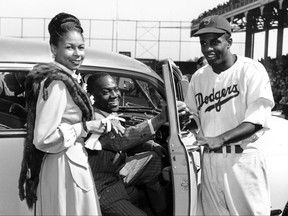 FILE - In this Sept. 23, 1947, file photo, Brooklyn Dodgers baseball player Jackie Robinson, right, receives the keys to a car from tap dancer Bill Bojangles Robinson as Jackie Robinson's wife, Rachel, looks on at Ebbets Field in New York. The car was presented to Robinson in celebration of the team winning the National League championship.  A rare jersey from Jackie Robinson's historic rookie season with the Brooklyn Dodgers 70 years ago could be available for someone with a few spare millions. The jersey, part of a Heroes of Sports offering by Heritage Auctions, has been certified by Mears, one of the top memorabilia authentication companies. It is accompanied by a letter from Robinson's widow, Rachel, saying it is the one brought home by the Hall of Famer at the end of the 1947 season, when he became the first black player in the majors and earned Rookie of the Year honors. (AP Photo/Harry Harris, File)