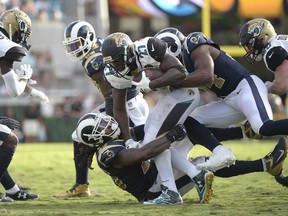 FILE - In this Oct. 15, 2017, file photo, Jacksonville Jaguars running back Leonard Fournette (27) is tackled by Los Angeles Rams linebacker Mark Barron (26) and outside linebacker Robert Quinn (94), right, during the first half of an NFL football game, in Jacksonville, Fla. After Fournette ripped off a 75-yard touchdown run on Jacksonville's first play, he was mostly held in check in the 27-17 loss. (AP Photo/Phelan M. Ebenhack, File)