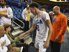 FILE - In this Nov. 20, 2016, file photo, UCLA's Lonzo Ball (2) greets his brother LaMelo Ball, left, after scoring 20 points in UCLA's 114-77 win over Long Beach State in an NCAA college basketball game in Los Angeles. Behind Lonzo Ball are his brother LiAngelo Ball and father, LaVar Ball, right. LaVar Ball is pulling 16-year-old LaMelo out of his Southern California high school to be home schooled and so he can be made into "the best basketball player ever." (AP Photo/Michael Owen Baker, File)