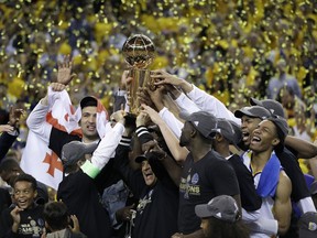 FILE - In this June 12, 2017, file photo, Golden State Warriors players, coaches and owners hold up the Larry O'Brien NBA Championship Trophy after Game 5 of basketball's NBA Finals between the Warriors and the Cleveland Cavaliers in Oakland, Calif. Winners of the NBA title in two of the last three seasons, Golden State made it look easy at times a year ago and prevailed in 31 of their final 33 games.  (AP Photo/Marcio Jose Sanchez, File)