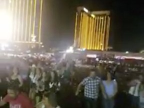 In this Sunday, Oct. 1, 2017 frame from video, people leave the scene of a deadly shooting in Las Vegas. Multiple victims were being transported to hospitals after a shooting late Sunday at a music festival on the Las Vegas Strip. (Shawn Kilgore via AP)