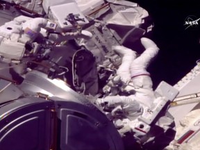 In this frame from NASA TV, Astronauts Mark Vande Hei and Randy Bresnik, right, emerge from the International Space Station on Tuesday, Oct. 10, 2017. The astronauts went out on a spacewalk to grease the robot arm's new hand. (NASA TV via AP)