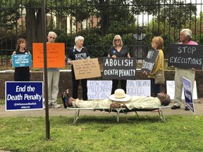 FILE - In this April 14, 2017, file photo, provided by Sherry Simon, Pulaski County Circuit Judge Wendell Griffen, lies on a cot at an anti-death penalty demonstration outside the Governor's Mansion in Little Rock, Ark. Griffen, who was barred from considering any execution-related cases after blocking the use of a lethal injection drug and participating in an anti-death penalty demonstration, is suing the state's highest court, saying justices violated his constitutional rights. (Sherry Simon via AP, File)