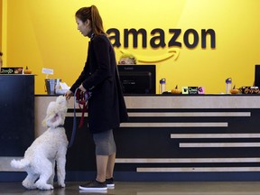 FILE - In this Wednesday, Oct. 11, 2017, file photo, an Amazon employee gives her dog a biscuit as the pair head into a company building, where dogs are welcome, in Seattle. Amazon says it received 238 proposals from cities and regions hoping to be the home of the company's second headquarters. The online retailer kicked off its hunt for a second headquarters in September, promising to bring 50,000 new jobs. It will announce a decision sometime in 2018. (AP Photo/Elaine Thompson, File)