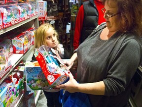 FILE - In this Friday, Nov. 27, 2015, file photo, Cinnamon Boffa, right, from Bensalem, Pa., checks out a "Chubby Puppies" toy for her daughter Serenity, left, at a Toys R Us, in New York. With some holiday toys already in stores, shoppers may want to start planning their strategy. (AP Photo/Bebeto Matthews, File)