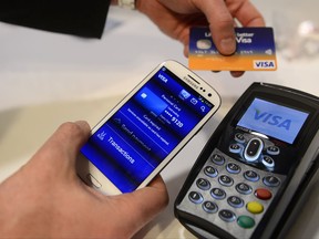 FILE - In this Wednesday, Feb. 27, 2013, file photo, a man uses the NFC payment Visa system at the Mobile World Congress, the world's largest mobile phone trade show, in Barcelona, Spain. Payment processing giant Visa is launching a platform to allow banks to integrate various types of biometrics, such as your fingerprint, face, voice, etc., into approving credit card applications and payments. It could lead to customers having to take a selfie to verify they actually made an online purchase or applied for a particular credit card. (AP Photo/Manu Fernandez, File)